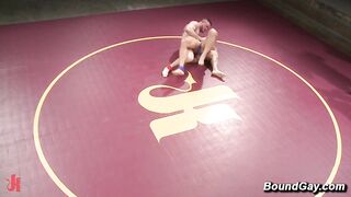 Seven Dixon und Mitch Vaughn ölen sich für einen Nacktkampf auf der lila Wrestlingmatte ein.